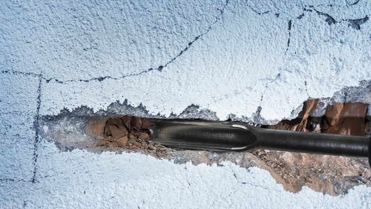 PRO SDS max Hollow Gouging Chisel, 26 x 300 mm Chisel tool breaking plaster on a painted wall.