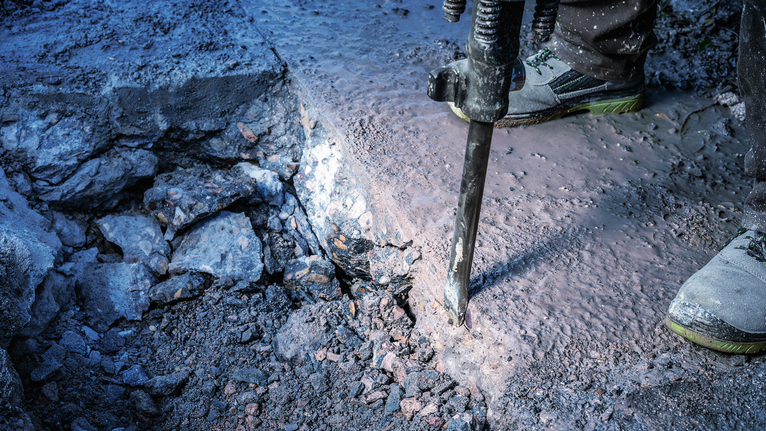 PRO HEX-4C Flat Chisel 30 mm, 35 x 400 mm A person wearing safety equipment uses a demolition tool to break concrete.