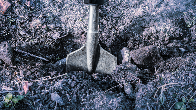 Flat chisel breaking hard soil outdoors.