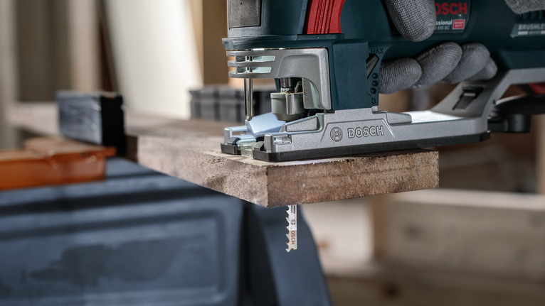 PRO Hardwood fast T144DF Jigsaw Blade, 100 mm, 5 pcs Person wearing safety equipment uses a jigsaw to cut a wooden board.