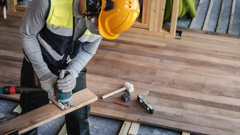 PRO Hardwood fast T144DF Jigsaw Blade, 100 mm, 5 pcs A person wearing safety equipment uses a jigsaw to cut wood flooring.