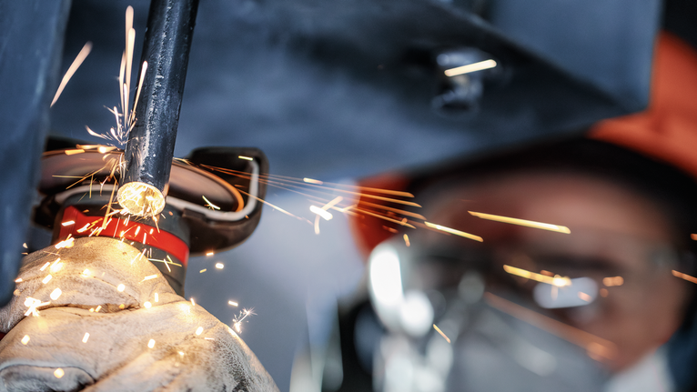 PRO Stainless Steel and Metal Bonded Cutting Disc, 76 x 1 x 10 mm Person wearing safety equipment grinds metal pipe, producing bright sparks.