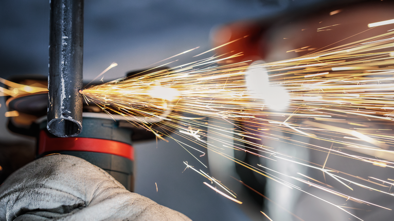 PRO Stainless Steel and Metal Bonded Cutting Disc, 76 x 1 x 10 mm Person wearing safety equipment grinds metal pipe, producing bright sparks.