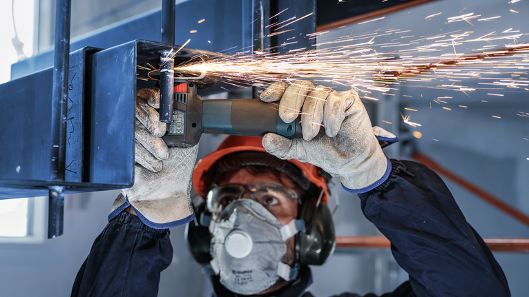 PRO Stainless Steel and Metal Bonded Cutting Disc, 76 x 1 x 10 mm Person wearing safety equipment grinds metal, creating sparks.