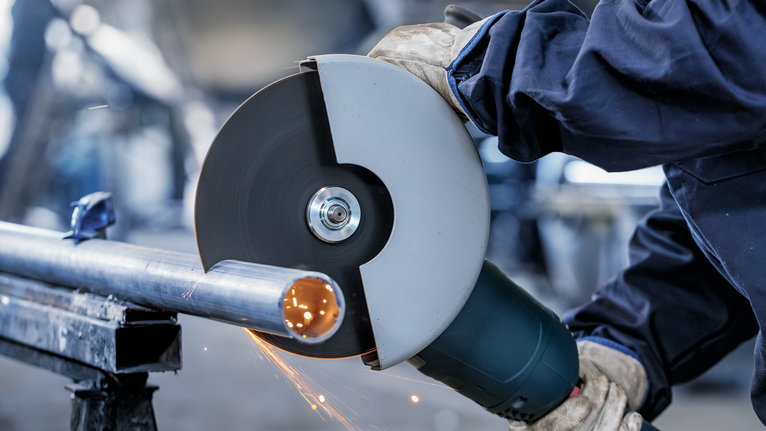 PRO Stainless Steel and Metal Bonded Cutting Disc, 230 x 1.9 x 22.23 mm, Straight Person wearing safety equipment cuts a metal pipe with a large angle grinder.