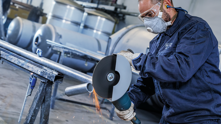 PRO Stainless Steel and Metal Bonded Cutting Disc, 230 x 1.9 x 22.23 mm, Straight A person wearing safety equipment cuts a metal pipe with a large angle grinder.