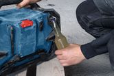 A person uses a portable jobsite radio to open a glass bottle on a construction site.