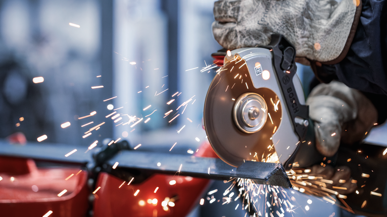 PRO Metal Bonded Cutting Disc, 125 x 2.5 x 22.23 mm, X-Lock, Straight Person wearing safety equipment uses an angle grinder to cut metal, producing sparks.