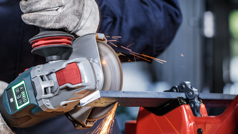 PRO Metal Bonded Cutting Disc, 125 x 2.5 x 22.23 mm, X-Lock, Straight A person wearing safety equipment grinds metal with an angle grinder, creating sparks.