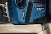 Close-up of a blue chainsaw resting on a wooden surface.