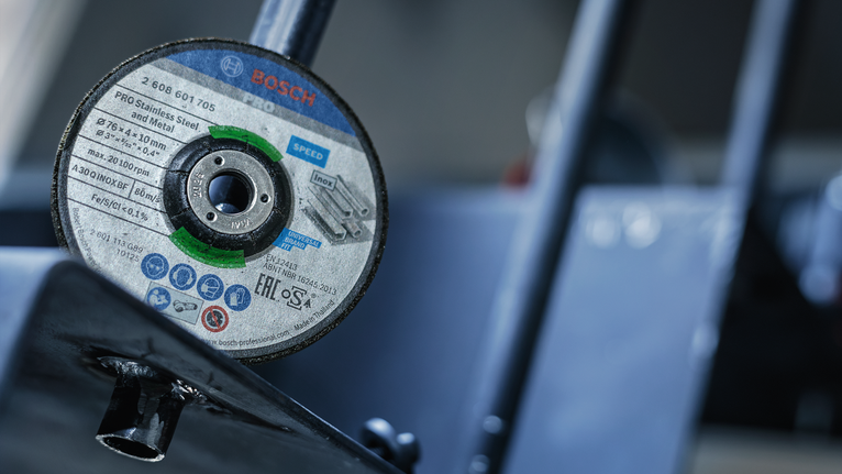 PRO Stainless Steel and Metal Grinding Disc, 76 x 4 x 10 mm A close-up of a cutting disc mounted on a metal tool in a workshop.