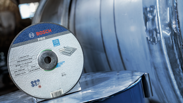 Cutting disc for stainless steel resting on a reflective metal surface.