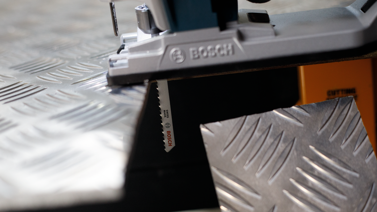 PRO Alu T127D Jigsaw Blade, 100 mm, 5 pcs Jigsaw cutting through a metal checker plate.