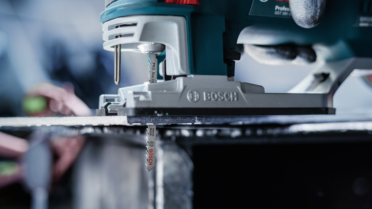 PRO Alu curve T227D Jigsaw Blade, 100 mm, 5 pcs Person wearing safety equipment guides a jigsaw cutting through a metal sheet.