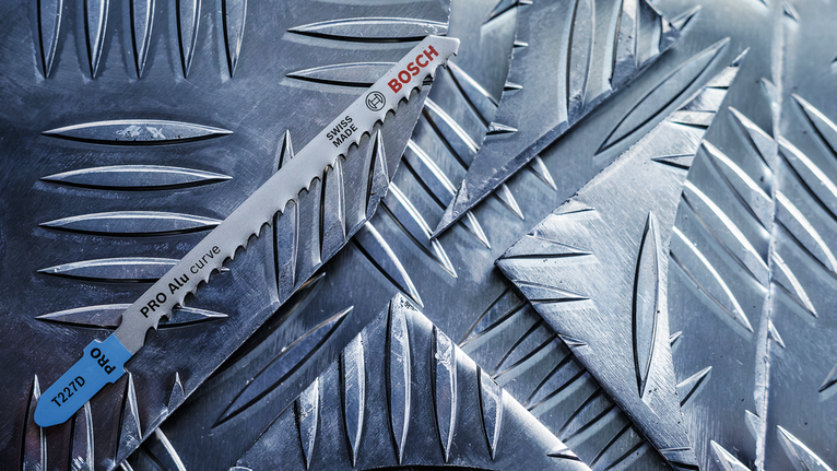 PRO Alu curve T227D Jigsaw Blade, 100 mm, 5 pcs Saw blade resting on textured metal sheets.