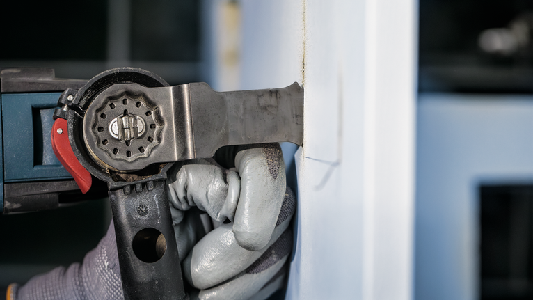 PRO AIZ 32 APIB Plunge Cut Blade, 32 x 50 mm Person wearing safety equipment uses a power tool to cut into a wall.
