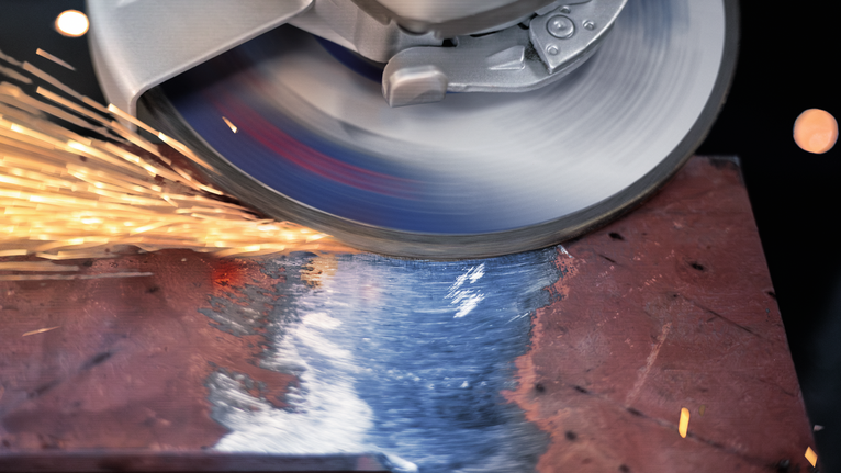 PRO Metal Grinding Disc, A 24 S BF, 180 x 6.6 x 22.23 mm, Depressed Centre A cutting disc grinds a metal sheet, producing bright sparks.