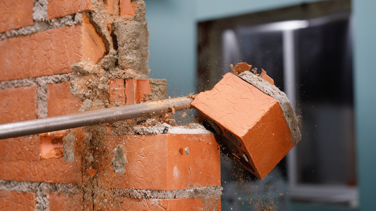 PRO SDS max-4C Flat Chisel, 25 x 600 mm Masonry chisel breaking a brick in a partially demolished wall.