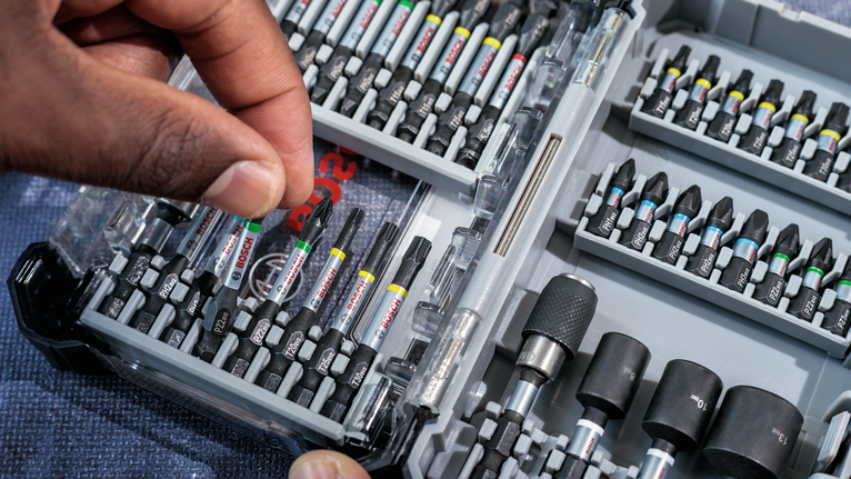 Person selects a screwdriver bit from an organized tool kit.