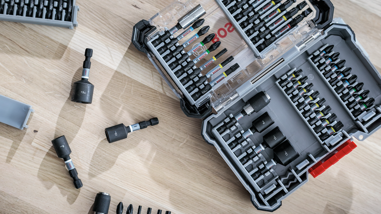 Open toolkit with various screwdriver bits and sockets arranged on a wooden surface.