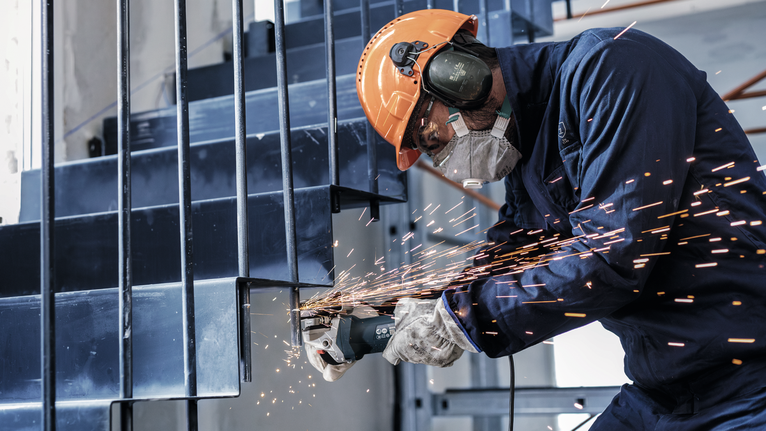 PRO Metal Cutting Disc, 100 x 2.5 x 16 mm Person wearing safety equipment grinds a metal staircase, sending sparks outward.