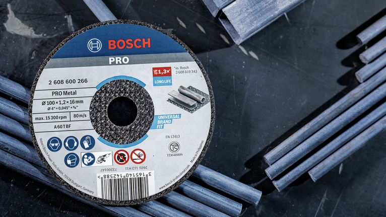 PRO Metal Cutting Disc, 100 x 2.5 x 16 mm Grinding disc placed on a dark surface with scattered metal rods.