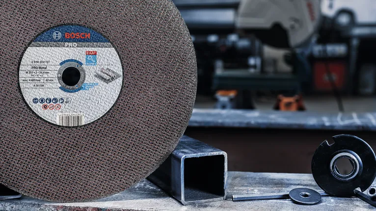 PRO Metal Cutting Disc, 355 x 3 x 25.4 mm Large abrasive cutting disc with metal parts nearby on a workshop table.