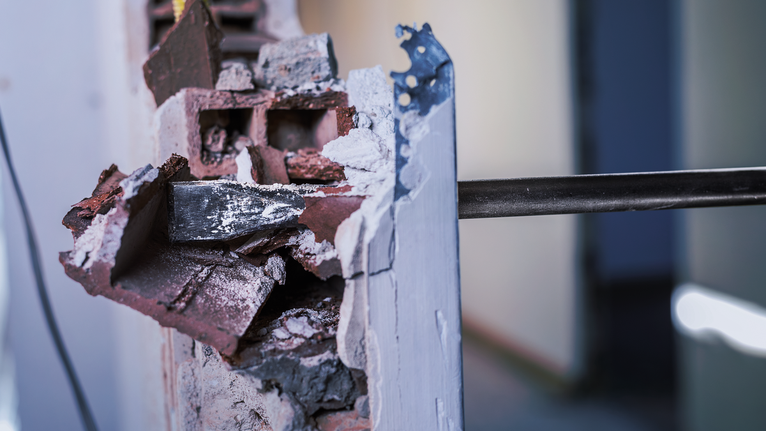 PRO SDS max-4C Flat Chisel, 25 x 600 mm Demolition tool breaking through a brick and plaster wall.