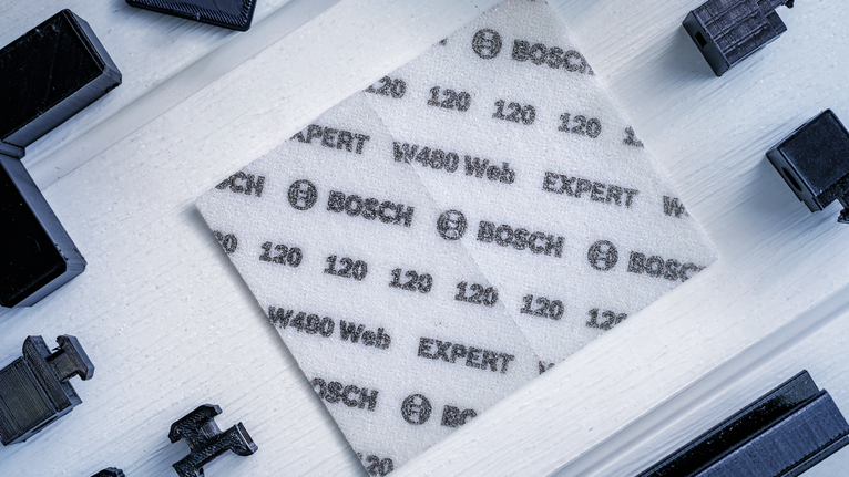 EXPERT W480 Web 1/4 Hand Sanding Sheet, 115 x 140 mm, G180 A white abrasive sanding sheet with printed specifications is placed on a light wooden surface.