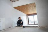 Person adjusting a laser leveling tool projects green lines in a partially finished room.