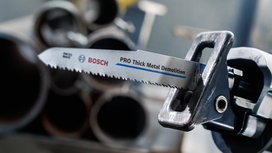 Reciprocating saw with a demolition blade positioned near metal pipes.
