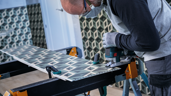 Object #200476167: 3066412_app_web_4 Person wearing safety equipment cuts patterned tile with a jigsaw on a workbench.