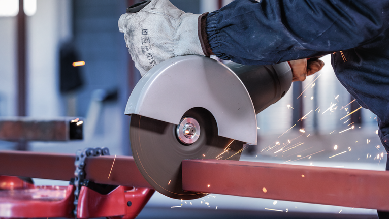 PRO Metal Cutting Disc, 180 x 3 x 22.23 mm Person wearing safety equipment cuts metal with a circular saw, sparks flying.