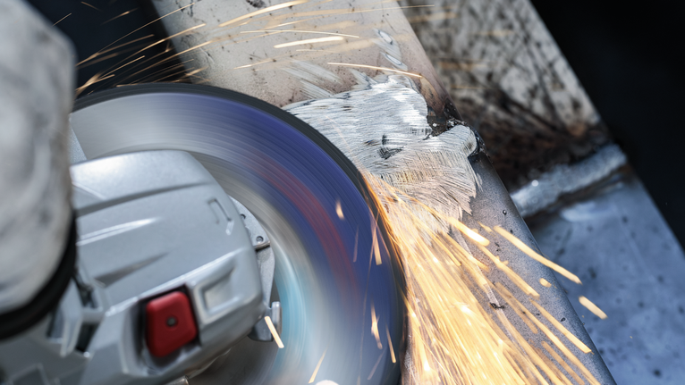 PRO Stainless Steel Grinding Disc, 100 x 6 x 16 mm Person wearing safety equipment grinds a metal surface, producing bright sparks.