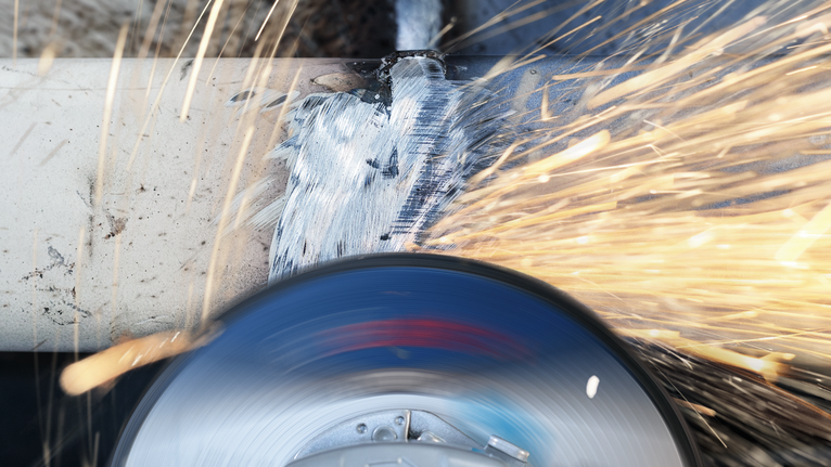 PRO Stainless Steel Grinding Disc, 100 x 6 x 16 mm A grinding tool smoothing a metal pipe with bright sparks flying.