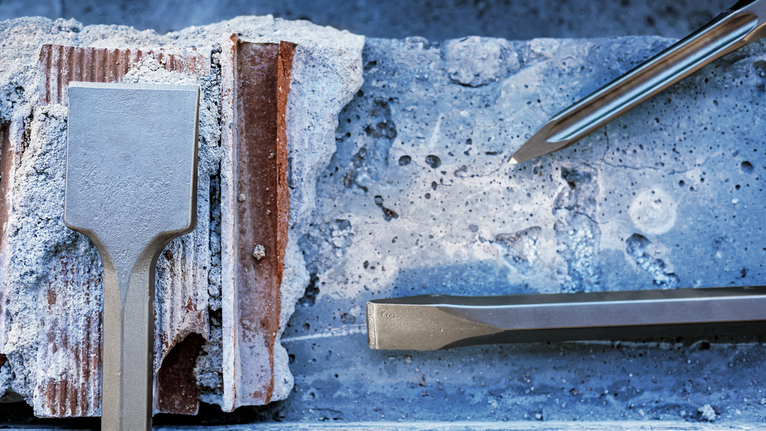 PRO HEX-4C Flat Chisel 28 mm, 35 x 520 mm Chisels breaking through a concrete block at a construction site.