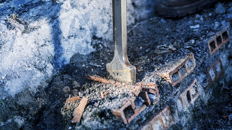 PRO HEX-4C Flat Chisel 28 mm, 35 x 520 mm Flat chisel breaking bricks on a rough concrete surface.