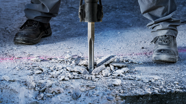 PRO HEX-4C Flat Chisel 28 mm, 35 x 520 mm Person wearing safety equipment breaks concrete with a demolition hammer.