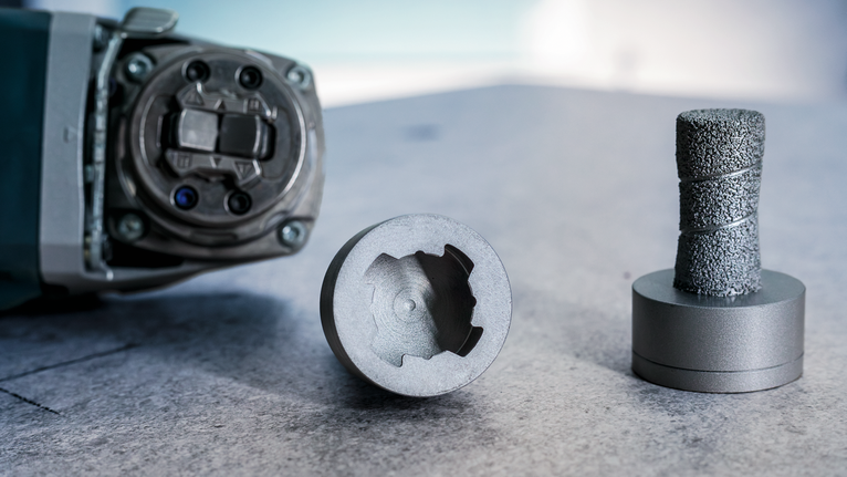 Rotary tool with a core bit and a grinding accessory placed on a work surface.