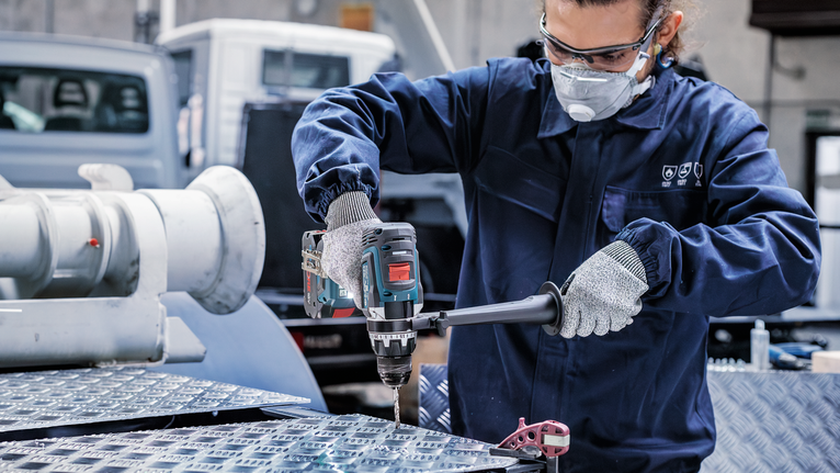 PRO Metal HSS-G Hex Twist Drill Bit Set, 5 pcs Person wearing safety equipment drills into a metal surface in an industrial setting.