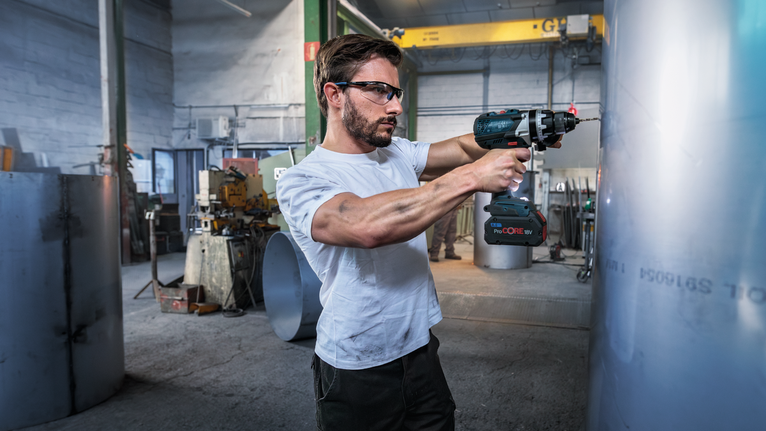PRO Stainless Steel HSS-Co Twist Drill Bit Set, 19 pcs Person wearing safety equipment drills into a large metal cylinder in an industrial workshop.
