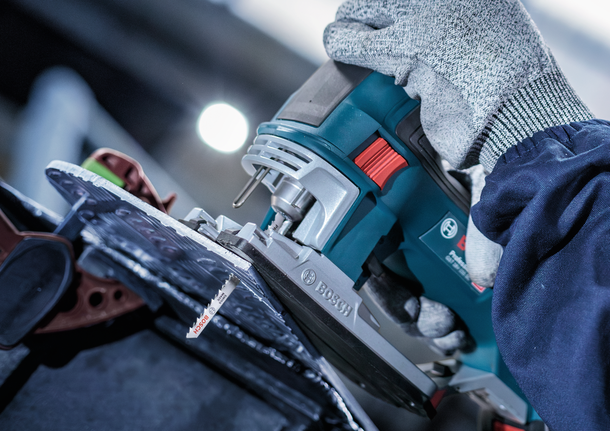 PRO Alu curve T227D Jigsaw Blade, 100 mm, 5 pcs Person wearing safety equipment uses a jigsaw to cut through a sheet material.