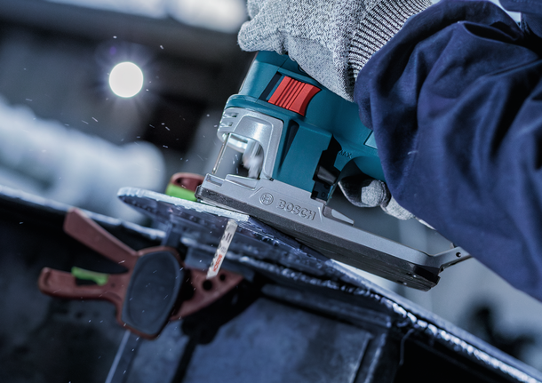 PRO Alu curve T227D Jigsaw Blade, 100 mm, 5 pcs A person wearing safety equipment uses a jigsaw to cut through a metal sheet.