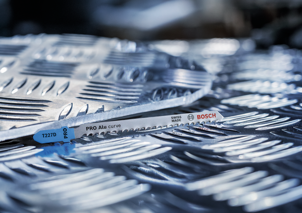 PRO Alu curve T227D Jigsaw Blade, 100 mm, 5 pcs Metal jigsaw blade resting on textured aluminum sheet.