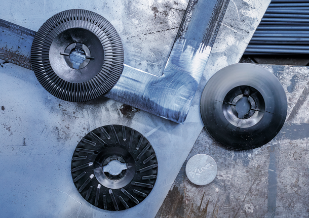 PRO Backing Pad Clip, X-Lock Three metal grinding and cutting discs arranged on a scratched metal surface.