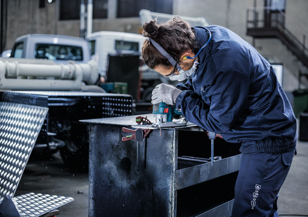 PRO Alu curve T227D Jigsaw Blade, 100 mm, 5 pcs Person wearing safety equipment drills metal on a workbench in an industrial workshop.