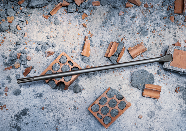 PRO SDS max-4C Flat Chisel, 25 x 600 mm Chisel bit lying on broken bricks and concrete debris.