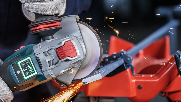 PRO Metal Bonded Cutting Disc, 125 x 2.5 x 22.23 mm, X-Lock, Straight Person wearing safety equipment uses an angle grinder to cut a metal bar.