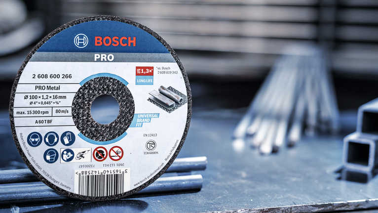 PRO Metal Cutting Disc, 100 x 2.5 x 16 mm Metal cutting disc on a workbench beside steel rods in a workshop.