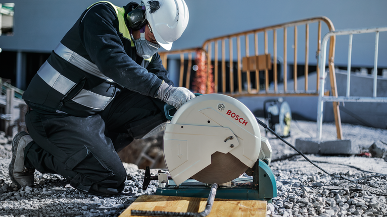 PRO Metal Cutting Disc, 355 x 3 x 25.4 mm A worker wearing safety equipment cuts rebar with a chop saw at a construction site.